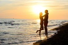 Romantic Young Couple In Love Together In The Sand Along The Beach Of Mediterranean Sea Sunset Backlight