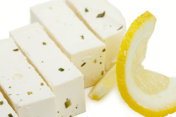 Blocks of greek feta cheese with greens and slice of lemon isola