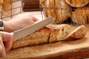 Woman cuts baguette on wooden board