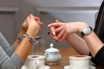 Two young women talking with cups of coffee on the table