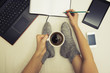 © grufnar - woman holding a cup of coffee taking a break from work on bed surrounded by multiple communication devices