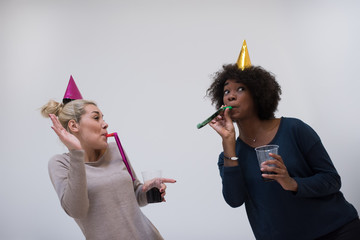 Wall Mural - smiling women in party caps blowing to whistles