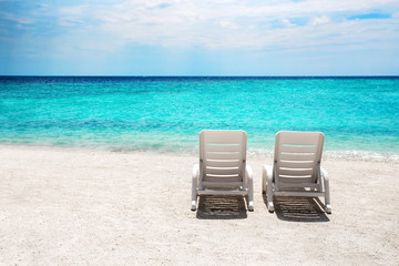 Two sun beds on white sand beach at tropical island