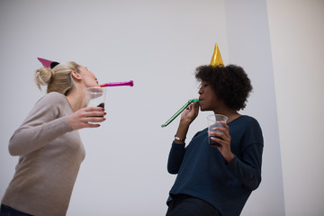 Wall Mural - smiling women in party caps blowing to whistles