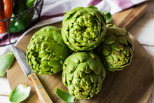 Fresh Green Artichokes On Cutting Board With Peeled Off Leaves,
