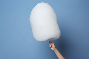 Wall Mural - Female hand holding cotton candy on blue background