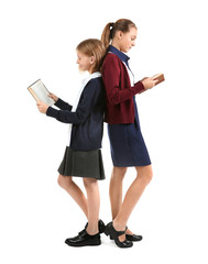 Wall Mural - Two cute girls in school uniform on white background