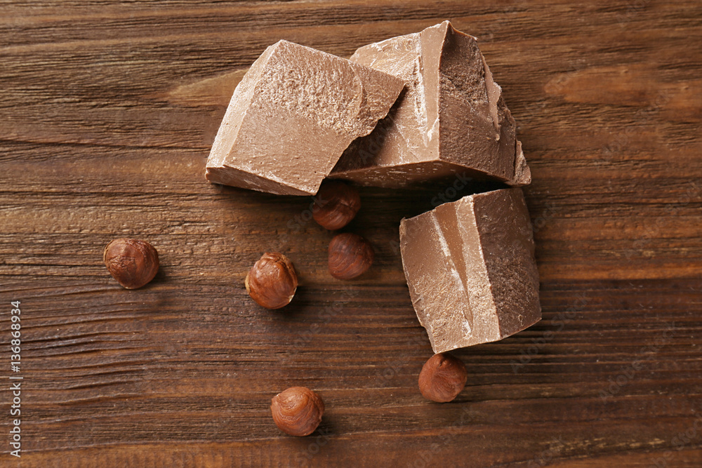 Chocolate pieces with nuts on wooden background