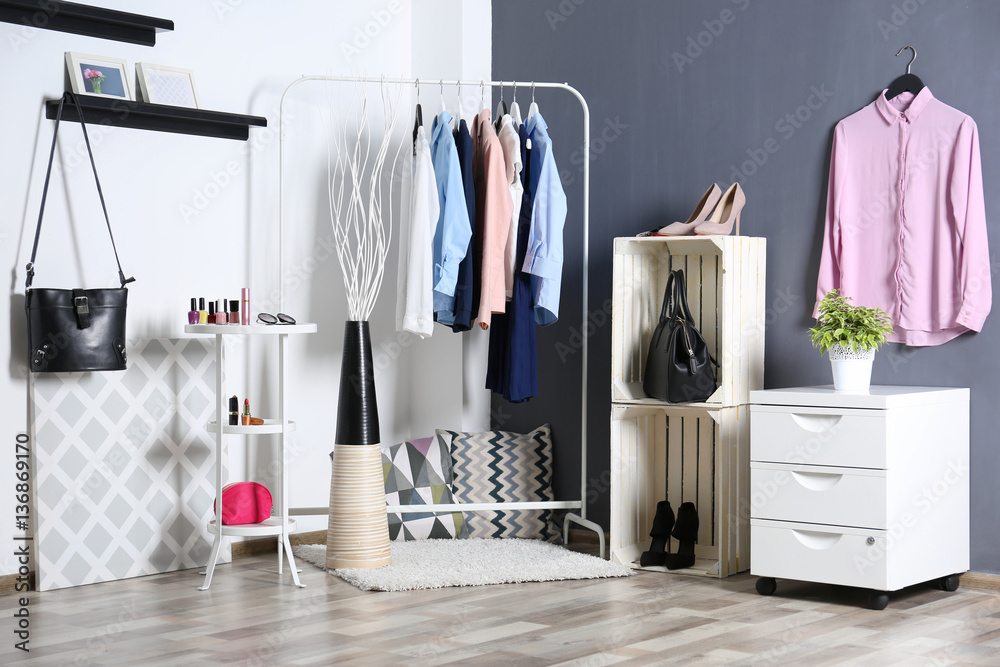 Fashionable clothes hanging on rack at modern dressing room