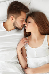 Wall Mural - Cute young couple lying in bed at home