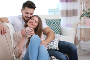 Wall Mural - Young couple sitting on sofa at home