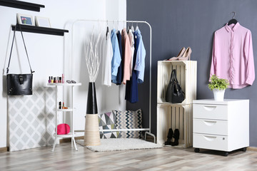 Fashionable clothes hanging on rack at modern dressing room