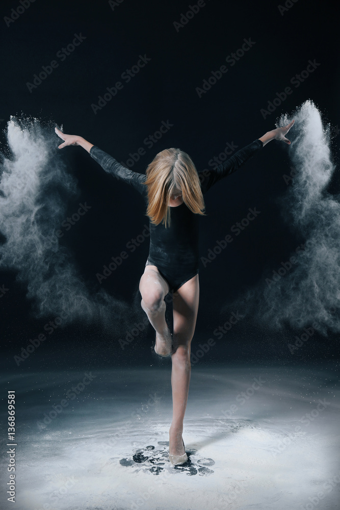Little cute girl dancing with white powder on black background