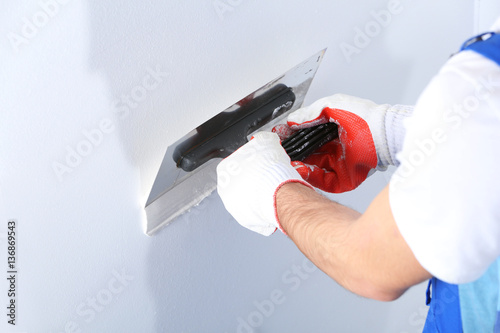 Cuadros en Lienzo Builder using plastering tool for finishing wall
