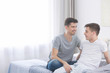 © Africa Studio - Happy gay couple sitting on bed at home