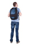 Fototapeta Las - Back view of man with  backpack looking up. Rear view people collection.  backside view of person.  Isolated over white background. guy in the green t-shirt stands with a suitcase on wheels