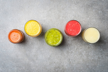 Wall Mural - Glasses of fresh juice on gray stone table. Food background