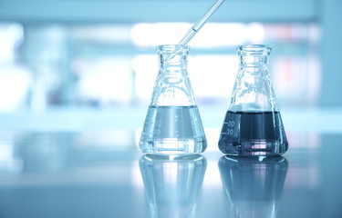 Wall Mural - two flask with pipet drop in water at science laboratory