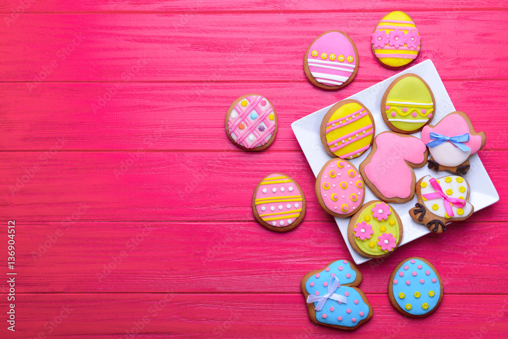Plate with delicious Easter cookies on red wooden background