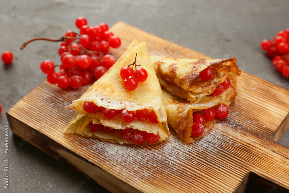 Delicious pancakes with viburnum on wooden board