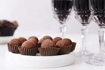 Canvas Print - Delicious chocolate truffles and red wine on white background