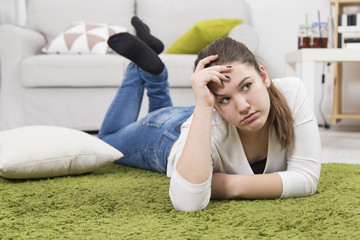 Young upset teenage girl lying on the floor. Teenage problems