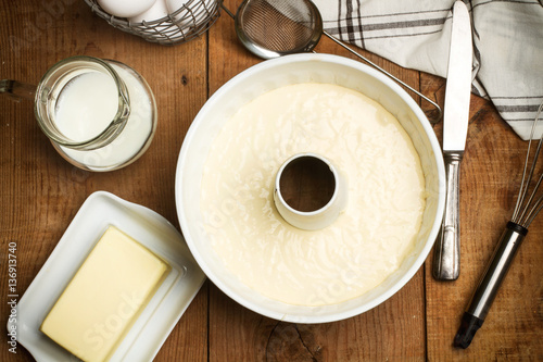 Fotomural Masa para bizcocho y torta con leche, mantequilla sobre mesa de madera rústica