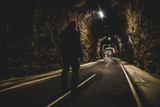 Fototapeta Londyn - man standing at the entrance of an illuminated tunnel - outdoor activity