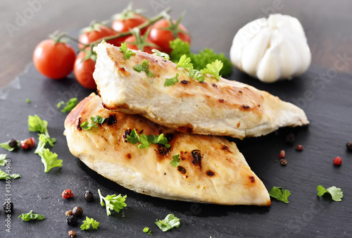 Fotografía Grilled chicken breast on a slate plate with herbs and cherry tomatoes, garlic and peppercorns