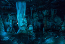 Speleothems With Blue Light In A Cave. It Is A Large Hollow Place In The Ground.