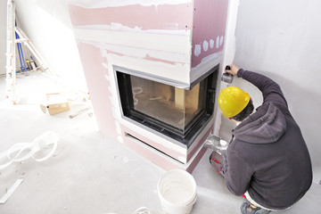 Wall Mural - Construction worker imposes a finishing coat on fire. Finishing the fireplace. Putting plaster.