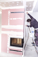 Wall Mural - Construction worker imposes a finishing coat on fire. Finishing the fireplace. Putting plaster.