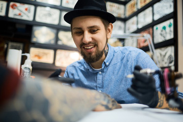 Wall Mural - Happy young tattoo artist at work