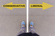 Conservative vs Liberal text arrows on asphalt ground, feet and