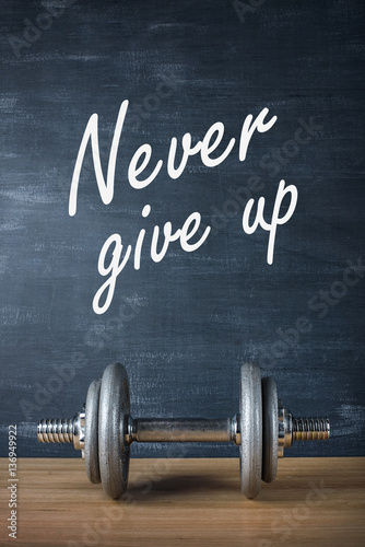 Fotografia metal barbell on dark gray background and motivation text never give up