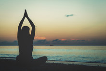 Young Woman Doing Yoga On Sunset Beach