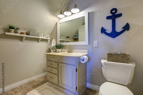 Fotografie, Obraz Marine style powder room interior in soft tones features vaulted ceiling over creamy white single bathroom vanity and toilet