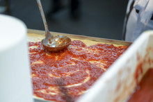 Pizzaiolo Puts Tomatoes On The Pizza With A Ladle