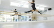 © Dash - Fit athletic young dancer leaping in the air as she practices in a dance studio in front of a large wall mirror  low angle with copy space.