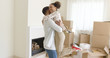 © Dash - Joyful young couple celebrating their move to a new home hugging and laughing in front of stacked boxes