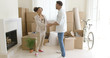 © Dash - Happy young couple congratulating each other as they stand in their new home surrounded by brown cardboard boxes