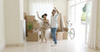 © Dash - Young couple dancing for joy in the living room of their new home with packing boxes behind them