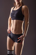 © mihakonceptcorn - A slender woman in a sports top and shorts on a gray background.