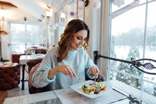 Smiling Woman Eating Fresh Salad In Restaurant