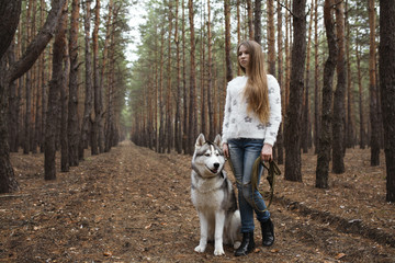 Red-haired girl with freckles walking with Husky dog in autumn f