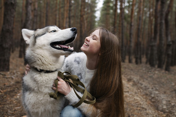 Red-haired girl with freckles walking with Husky dog in autumn f