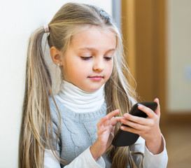 Wall Mural - Little girl with cell phone indoors.