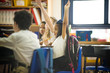 © Cavan Images - Students raising hands in the classroom