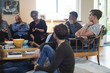 © Maskot - Multi-ethnic friends and family talking while sitting in living room