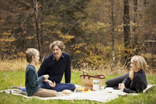 Parents And Son ( 8-9 ) Having Picnic In Forest